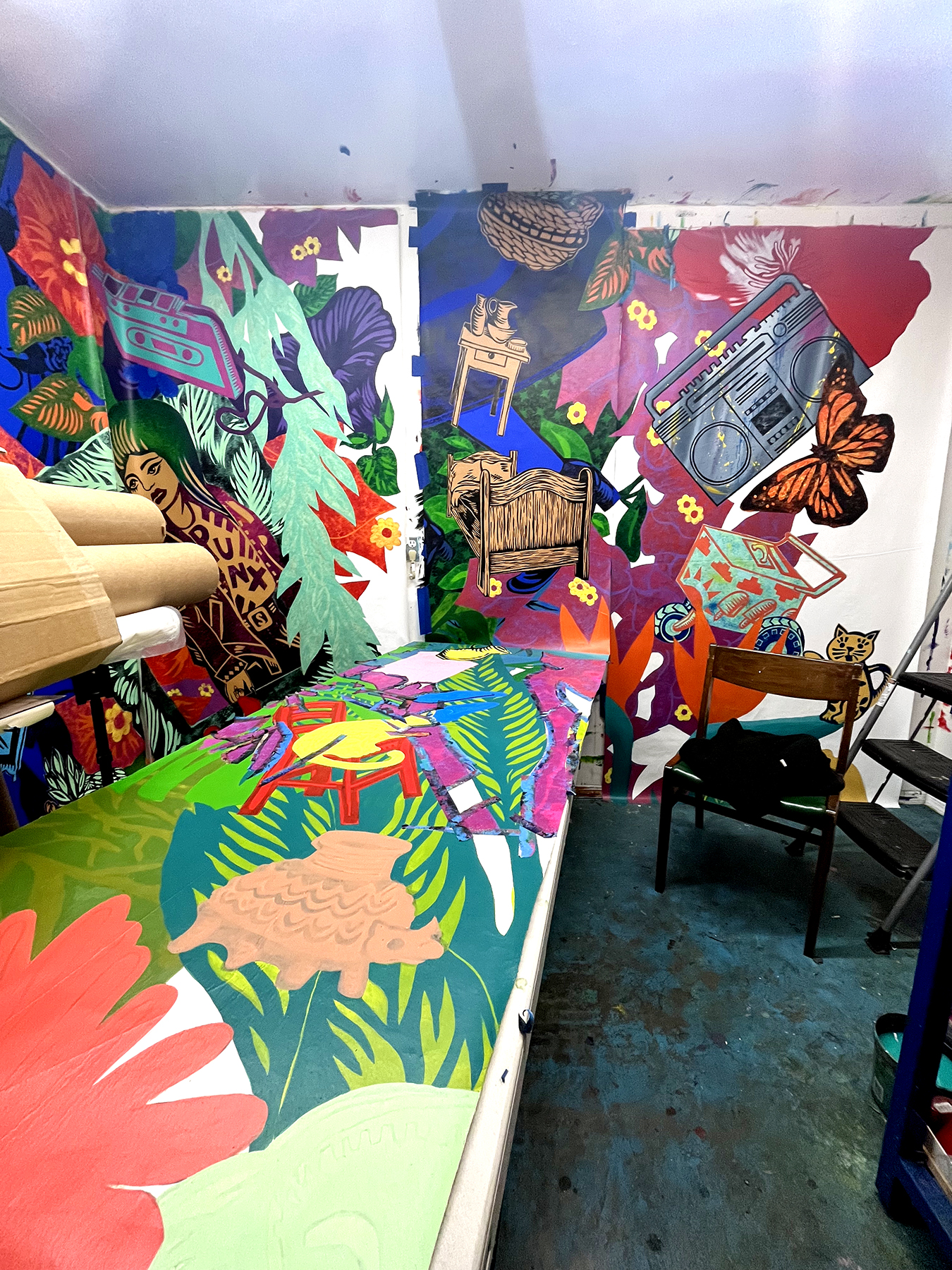 inside the artist's studio with colorful mural panels pinned to the wall